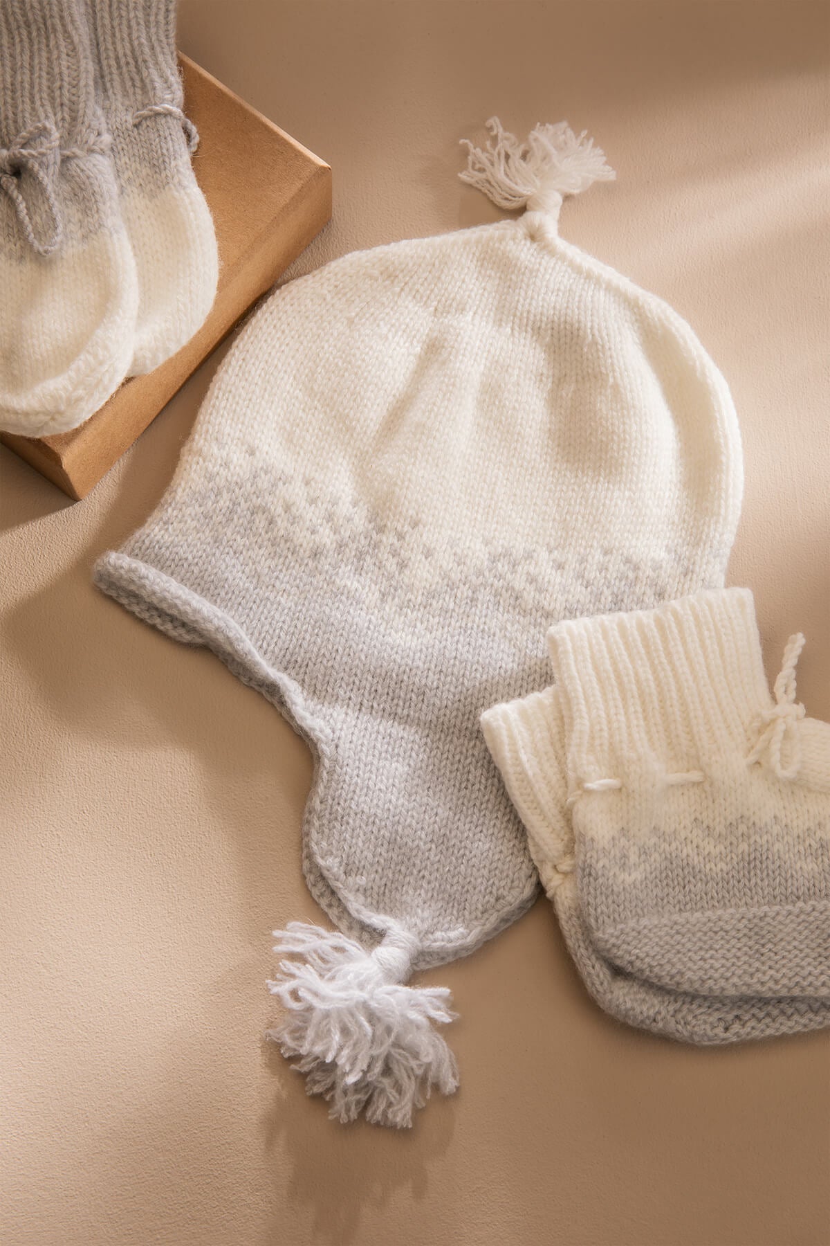 Johnstons of Elgin Gift Set includes our Cashmere Ombre Baby Hat, Mittens & Booties in Pumice on grey background AW21GIFTSET22A