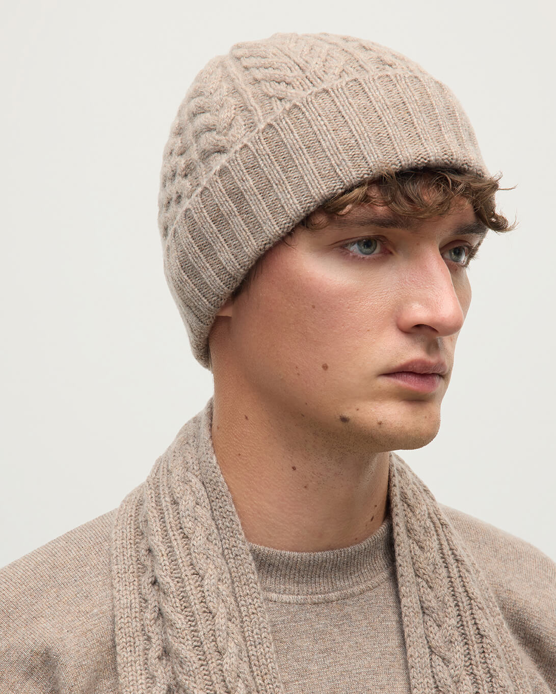 Model wears Johnstons of Elgin AW25 Knitted Accessories Ash Aran Cable Brown Cashmere Beanie HAC03411HB4334ONE