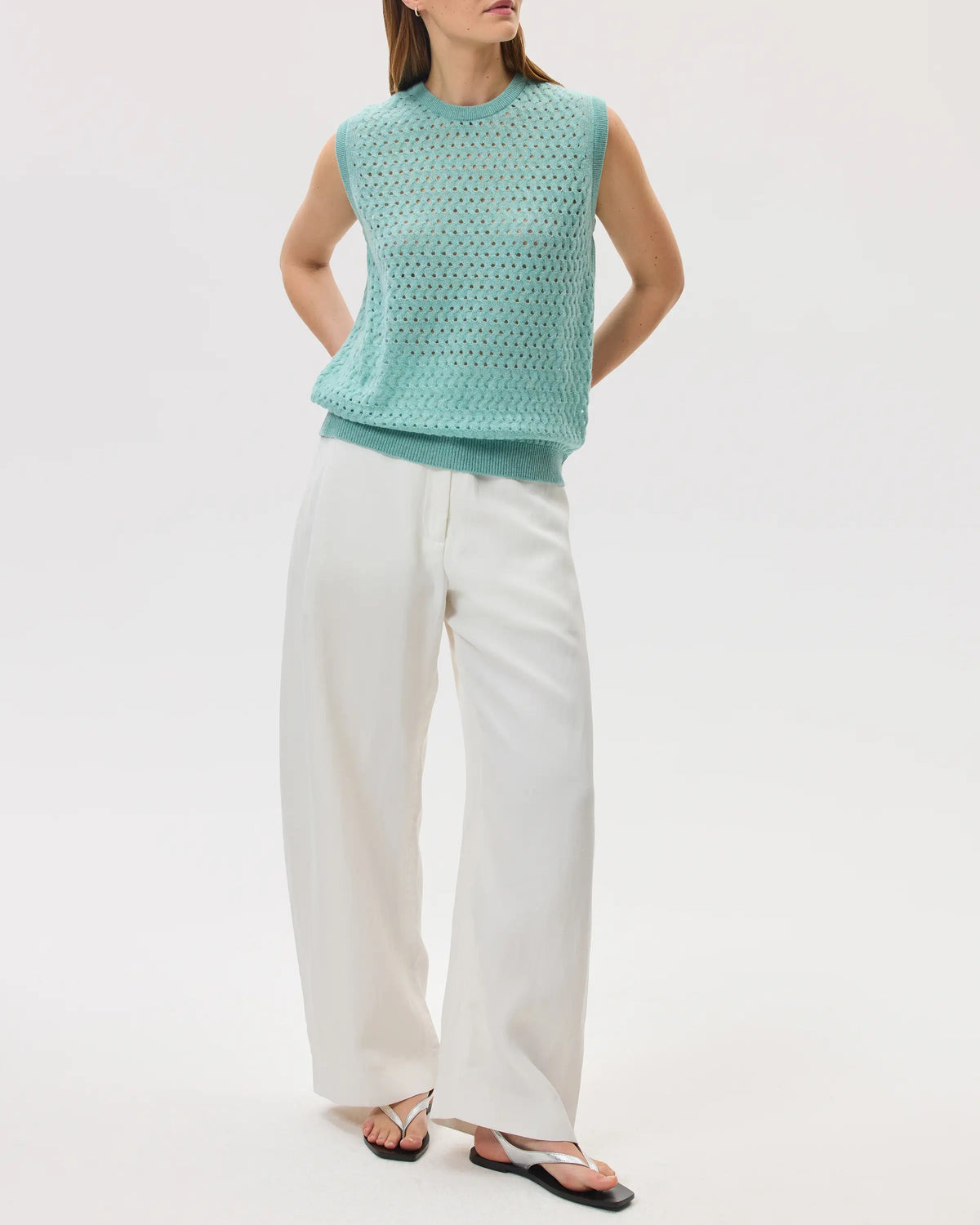 Model wearing Johnstons of Elgin SS25 Women's Knitwear Jade Open Basketweave Cashmere Tank with white jeans against a white backdrop KAA05429HC4284