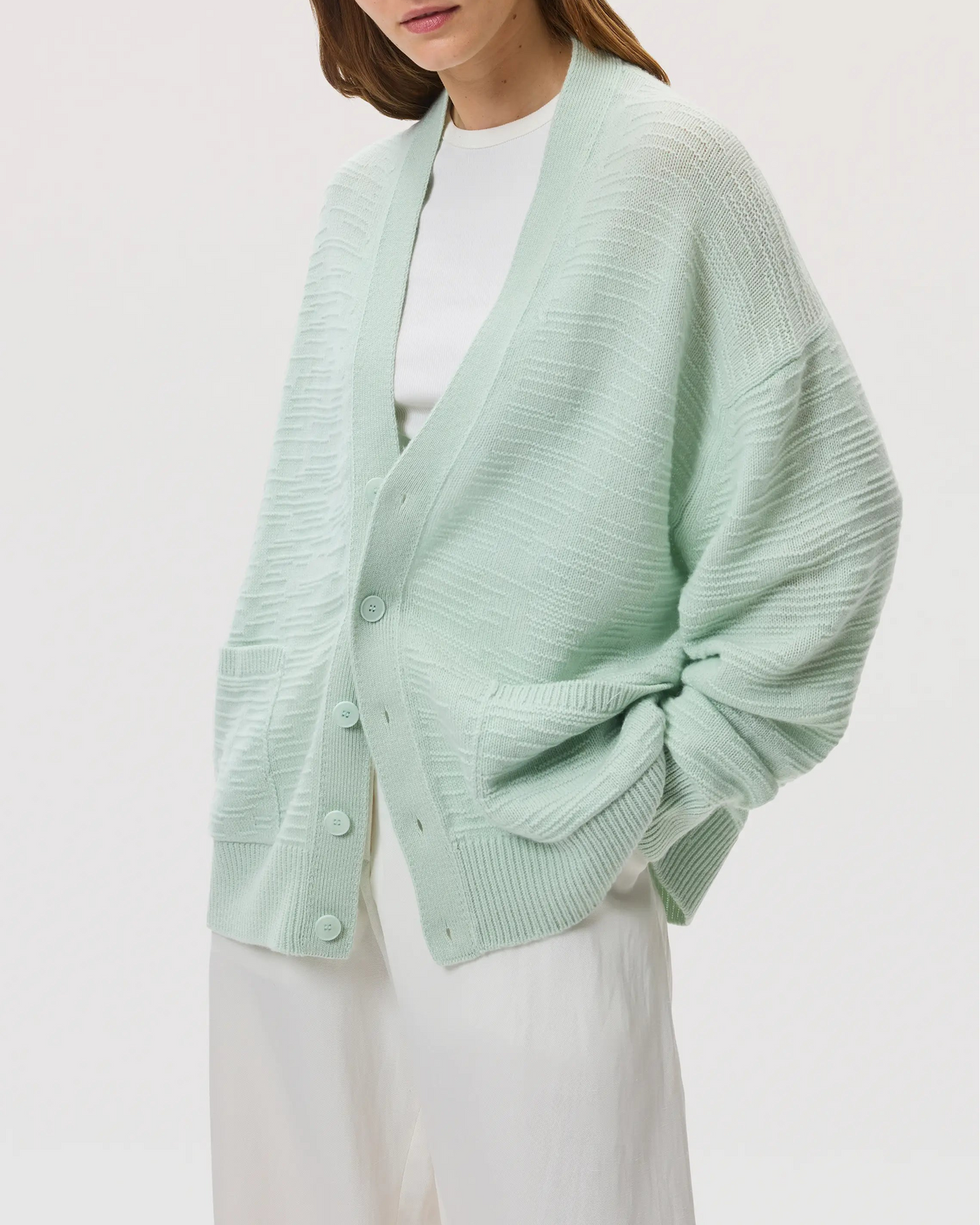 Female model wearing Johnstons of Elgin SS25 Unisex Knitwear Mint Textured Cashmere Cardigan with white t-shirt on a white background KAC05415SC0169