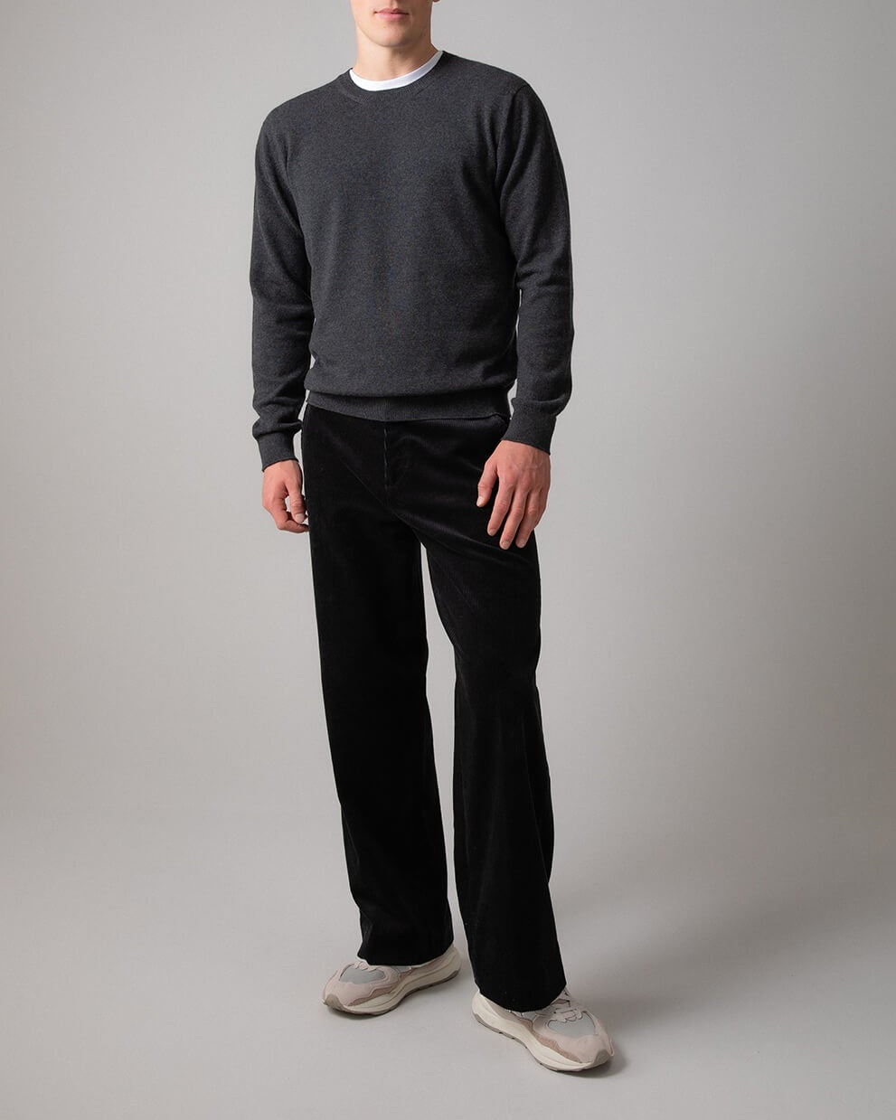 Johnstons of Elgin Men’s Cashmere Round Neck Jumper in Charcoal grey on model wearing black trousers on grey background KAI05117HA7165
