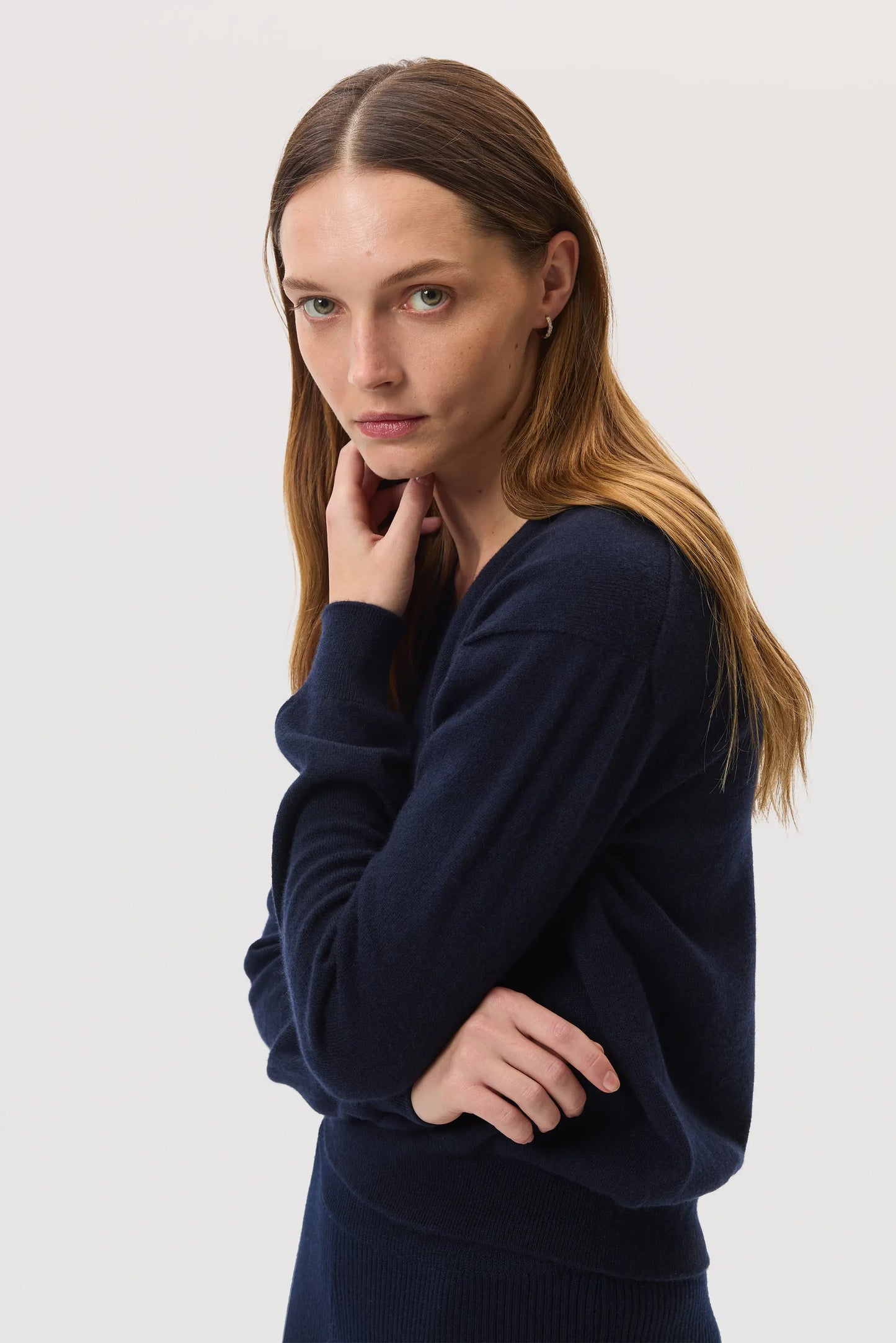 Model wearing Johnstons of Elgin SS25 Women's Knitwear Navy Classic Cashmere V Neck Sweater on a white background KAI05143SD7286