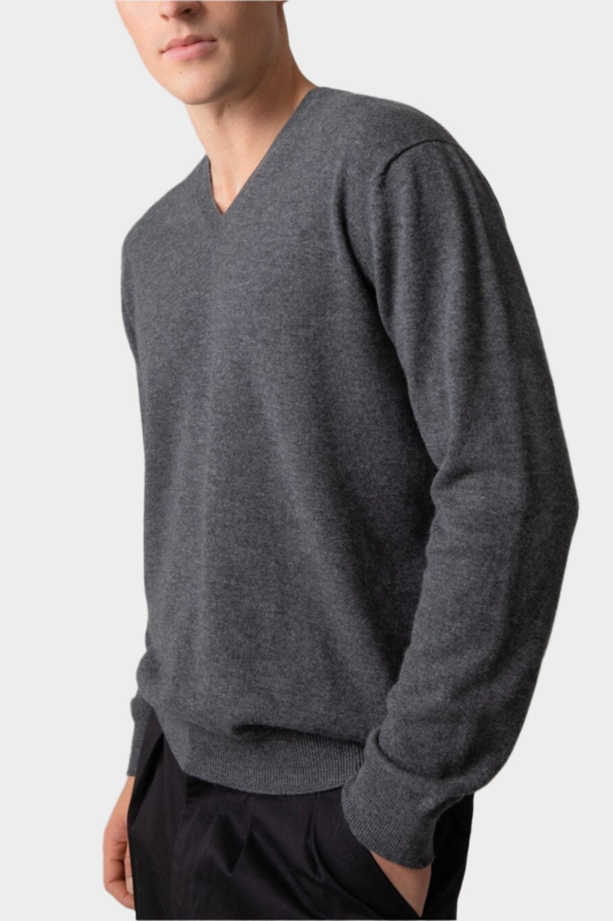 Johnstons of Elgin Men’s Cashmere V Neck Jumper in mid grey on model wearing navy trousers on grey background KAI05150HA4181
