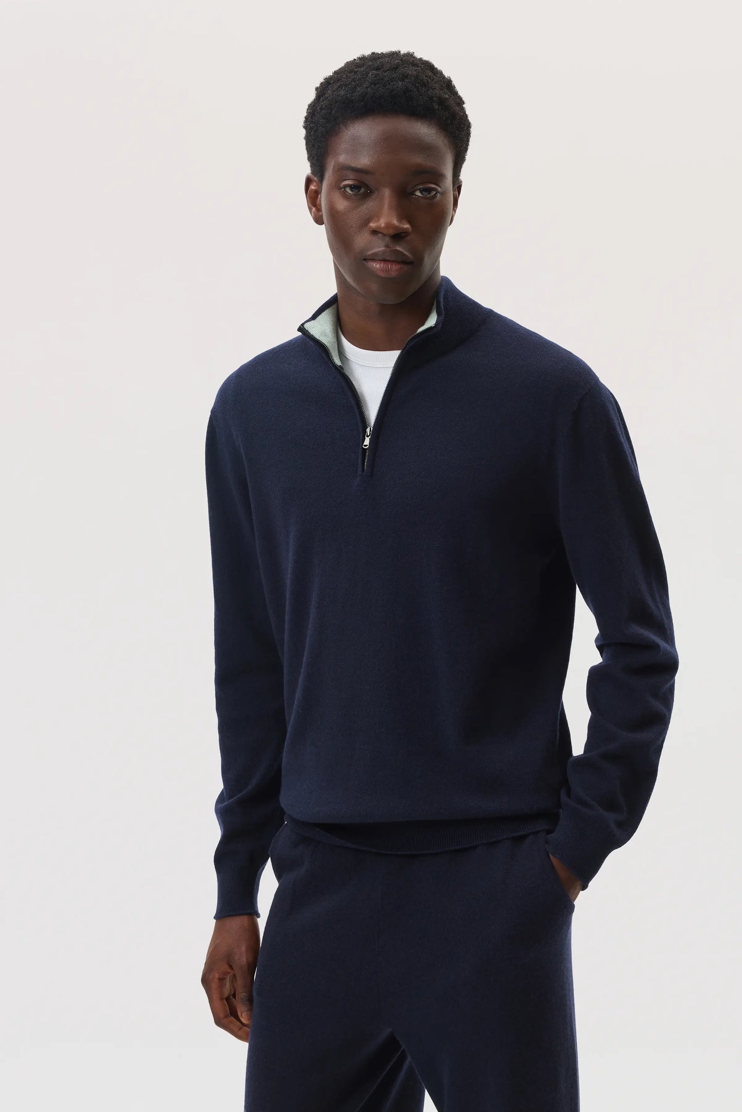 Model wearing Johnstons of Elgin SS25 Men's Knitwear Navy & Mint Contrast Trim Cashmere Zip Neck Sweater with navy cashmere joggers KAI05233Q25114