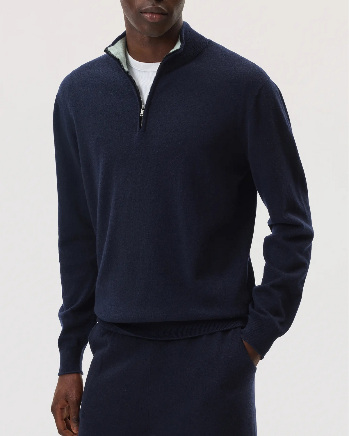 Model wearing Johnstons of Elgin SS25 Men's Knitwear Navy & Mint Contrast Trim Cashmere Zip Neck Sweater with navy cashmere joggers KAI05233Q25114