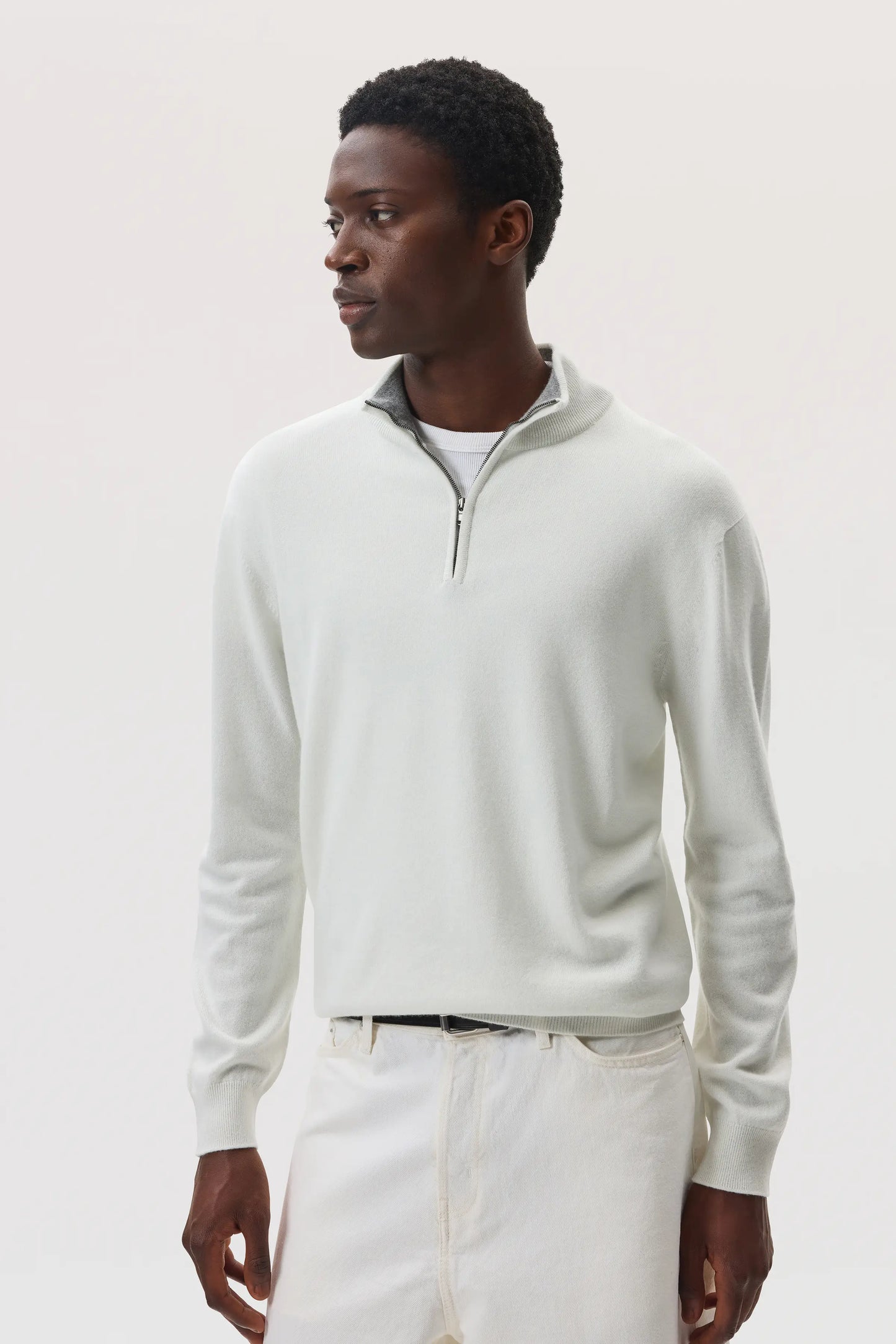 Model wearing Johnstons of Elgin SS25 Men's Knitwear White & Light Grey Contrast Trim Cashmere Zip Neck Jumper with white trousers KAI05233Q25115