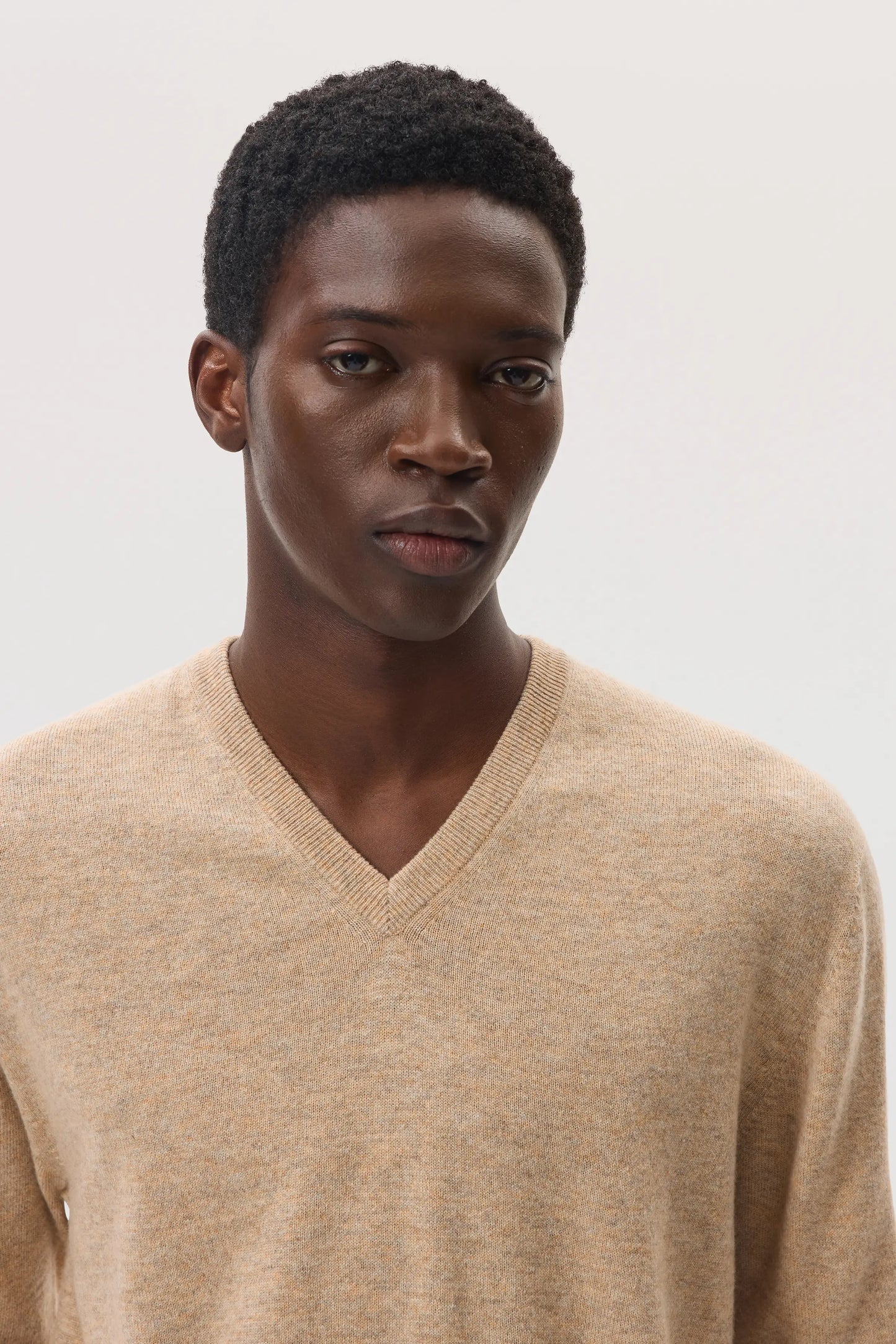 Model wearing Johnstons of Elgin SS25 Men's Knitwear Oatmeal Classic Cashmere V Neck Jumper KAI05266HB0210
