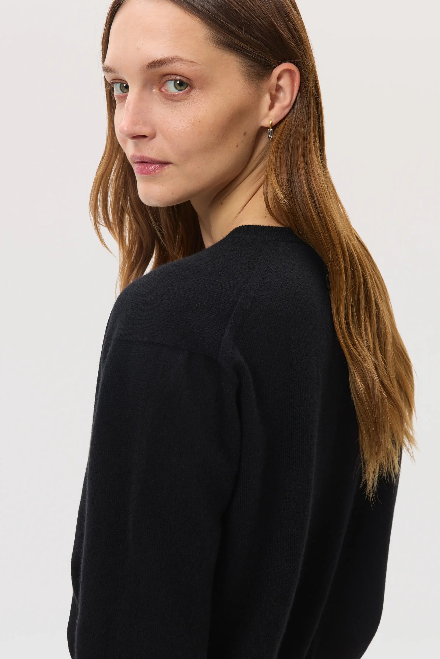 Models wears Johnstons of Elgin SS25 Women's Knitwear Black Classic Cashmere Cardigan on a white background KAI05274SA0900