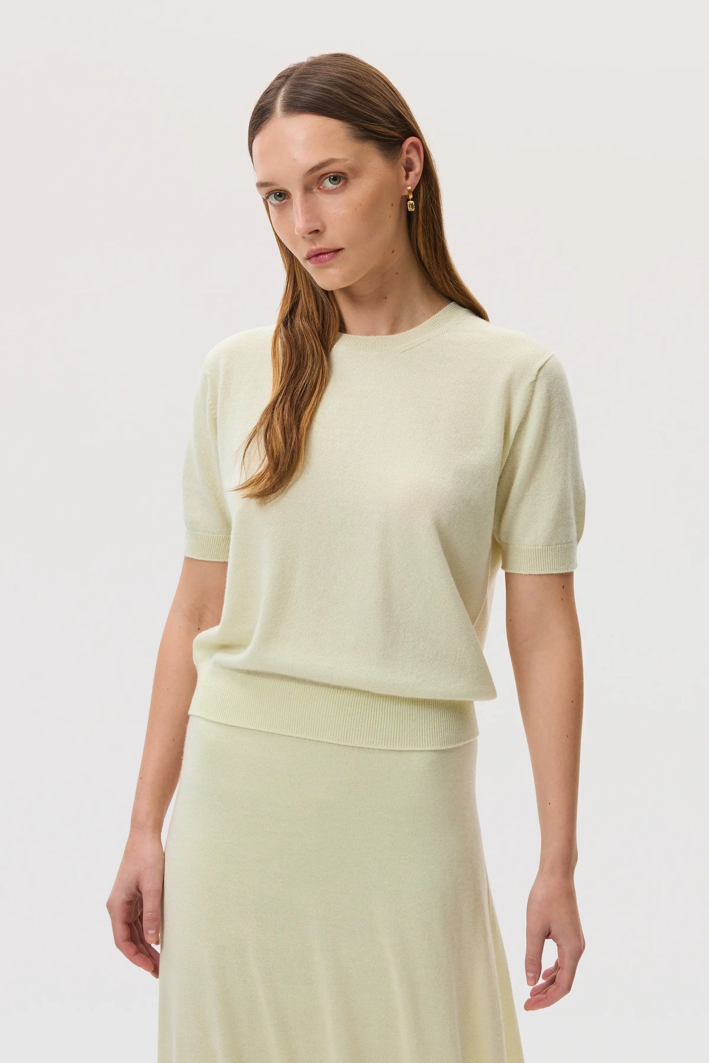 Model wears Johnstons of Elgin SS25 Women's Knitwear Lemon Classic Cashmere T-Shirt with matching cashmere silk skirt KAI05371SA0145