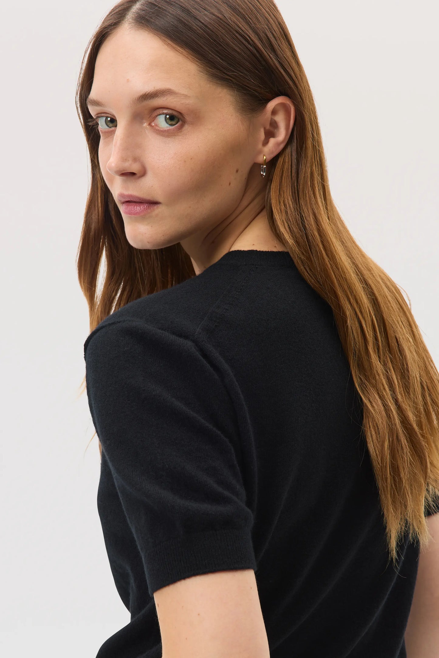 Model wears Johnstons of Elgin SS25 Women's Knitwear Black Classic Cashmere T-Shirt on a white backdrop KAI05371SA0900