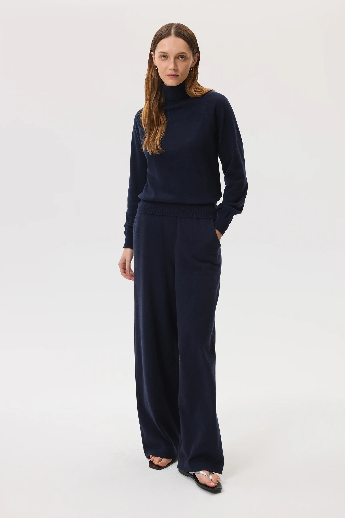 Model wears Johnstons of Elgin SS25 Women's Knitwear Navy Classic Cashmere Roll Neck Sweater with matching cashmere culottes on a white background KAP05275SD7286