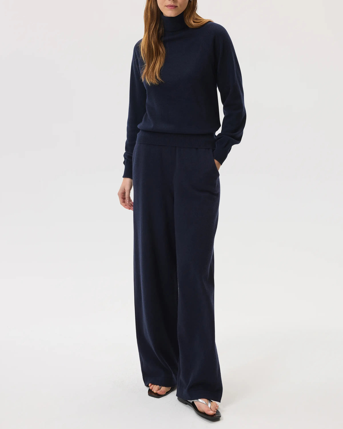 Model wears Johnstons of Elgin SS25 Women's Knitwear Navy Classic Cashmere Roll Neck Sweater with matching cashmere culottes on a white background KAP05275SD7286
