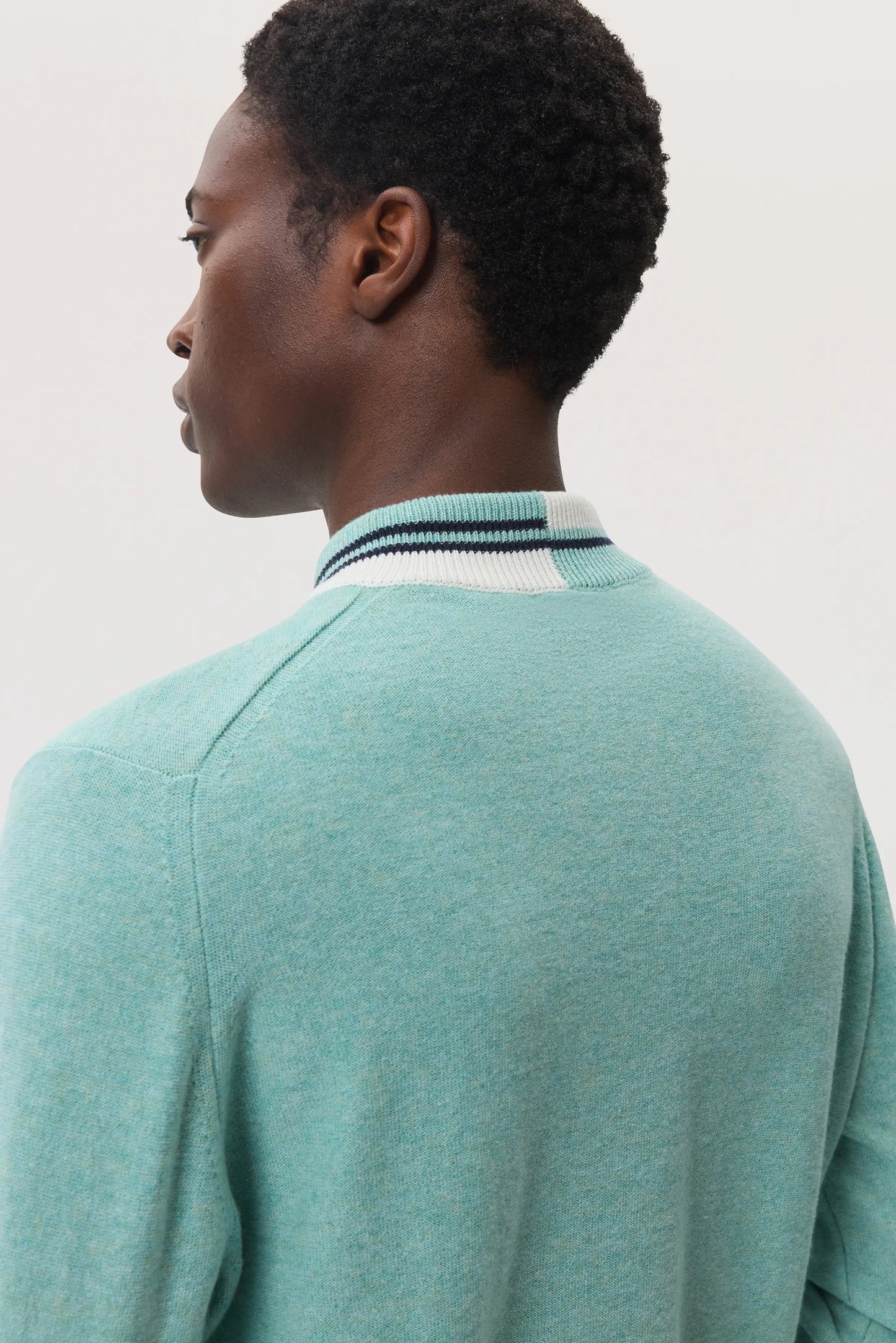 Model wears Johnstons of Elgin SS25 Men's Knitwear Jade Cashmere V Neck Jumper with Striped Trim on a white background KAP05410Q25122