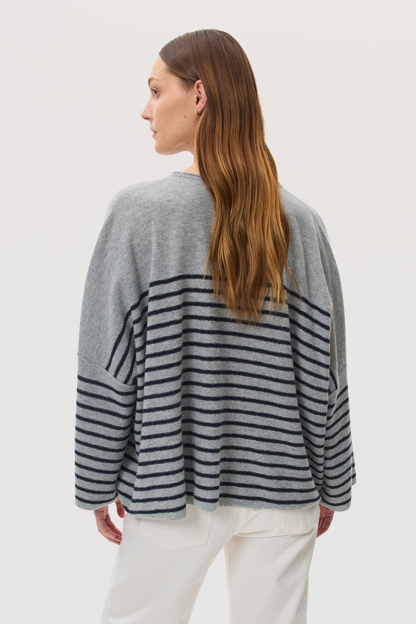 Model wears Johnstons of Elgin SS25 Women's Knitwear Light Grey & Navy Relaxed Featherlight Cashmere Stripe Jumper in a white studio location KAP05425Q25142