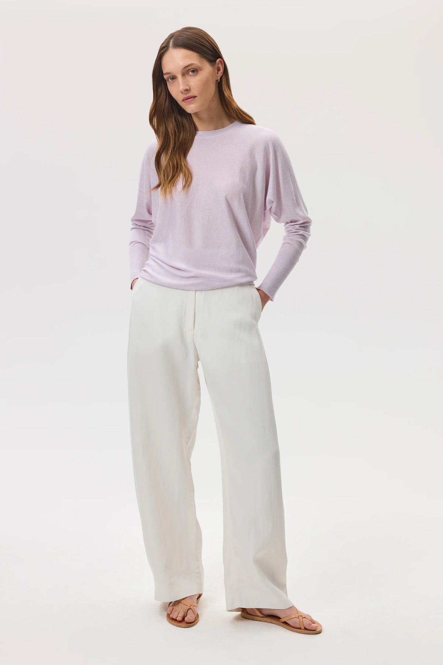 Johnstons of Elgin SS25 Women's Knitwear Lavender Cashmere Silk Batwing Jumper worn with white jeans on a pale grey backdrop KBI00975HD0088