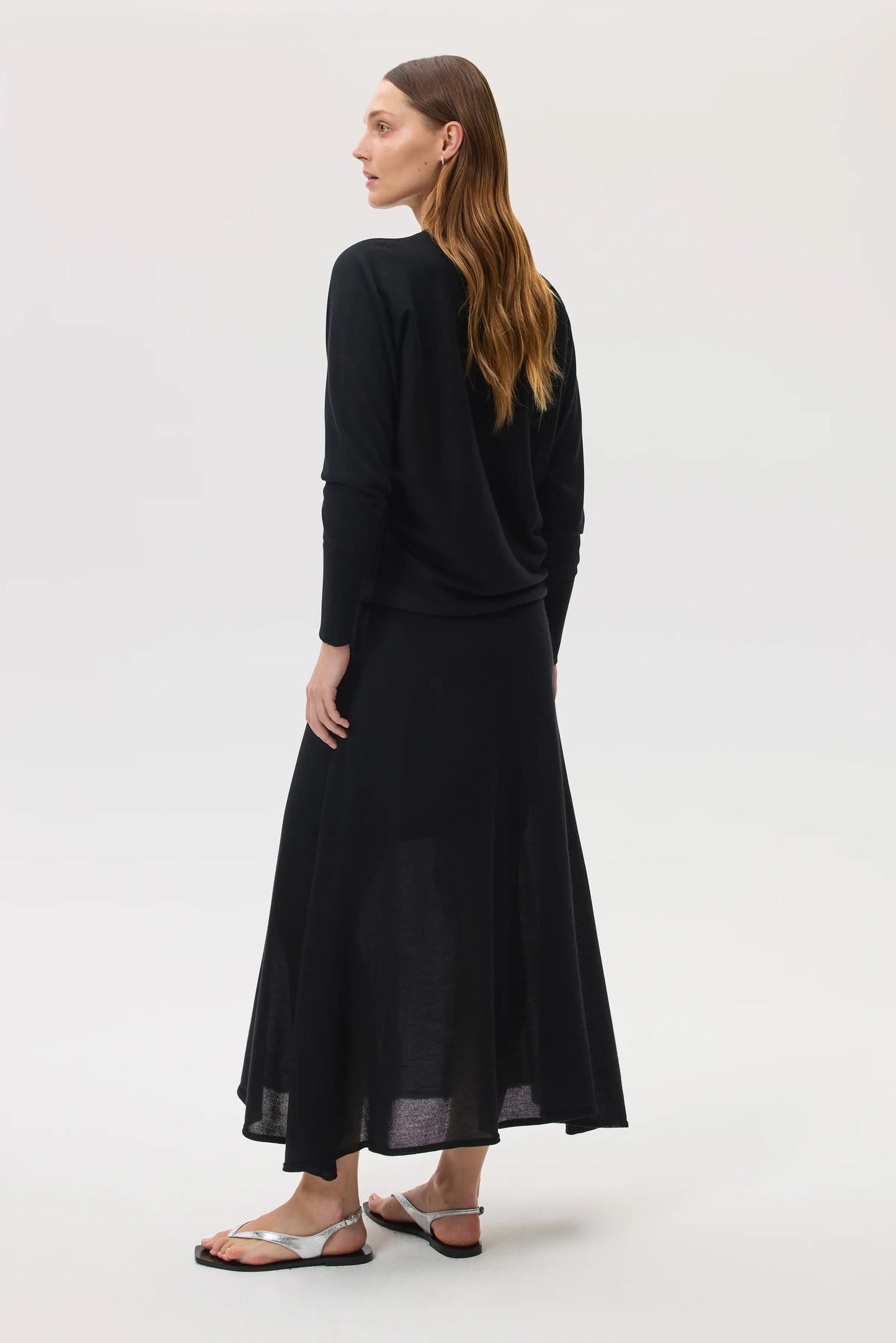 Model wearing Johnstons of Elgin SS25 Women's Knitwear Black Cashmere Silk A-Line Skirt with matching cashmere silk batwing jumper on a white background KBI00976SA0900