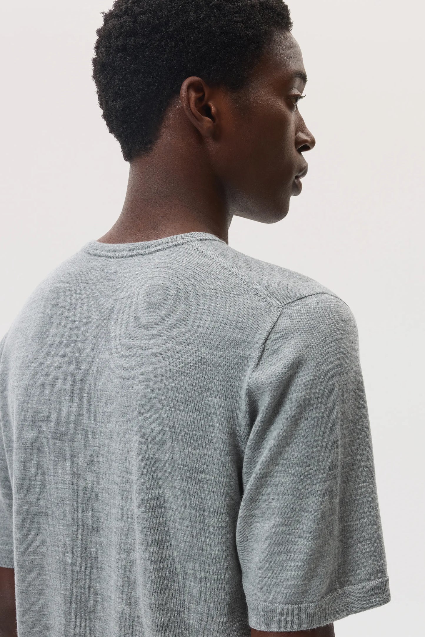 Model wears Johnstons of Elgin SS25 Men's Knitwear Light Grey Superfine Merino T-Shirt KDI00663HA4183