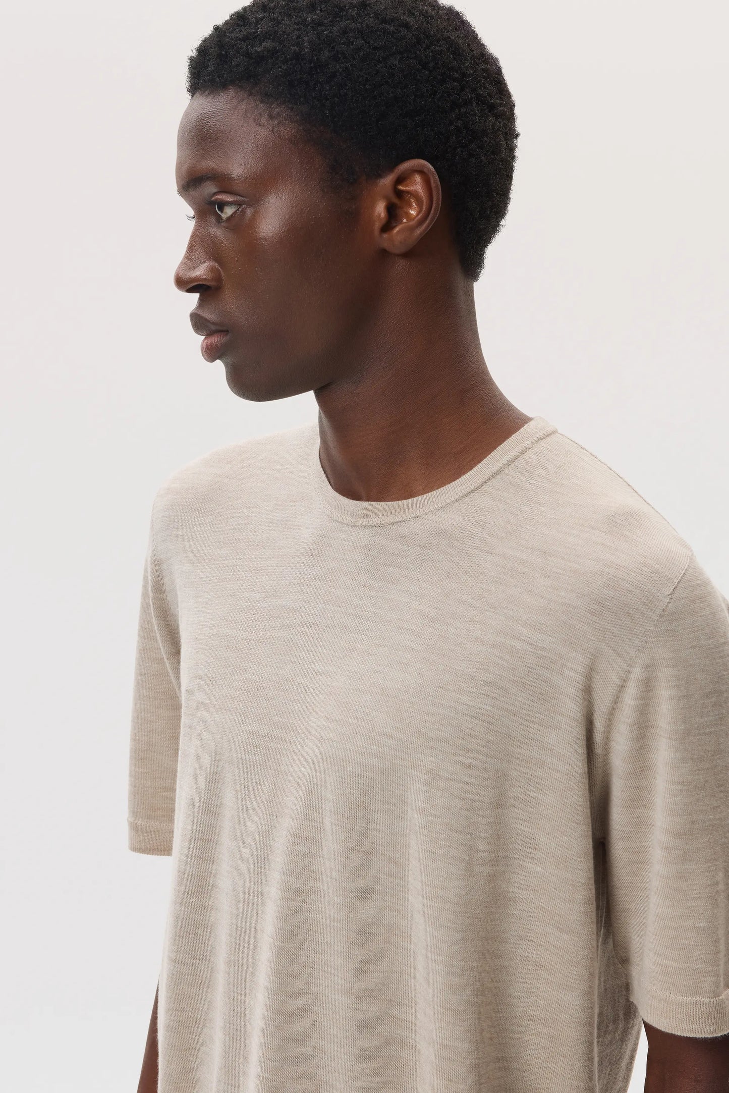 Model wears Johnstons of Elgin SS25 Men's Knitwear Natural Superfine Merino T-Shirt KDI00663SB0695