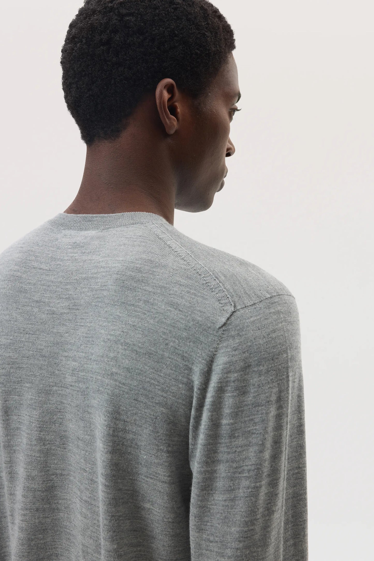 Model wears Johnstons of Elgin SS25 Men's Knitwear Light Grey Merino Round Neck Sweater against a white backdrop KDI00702HA4183