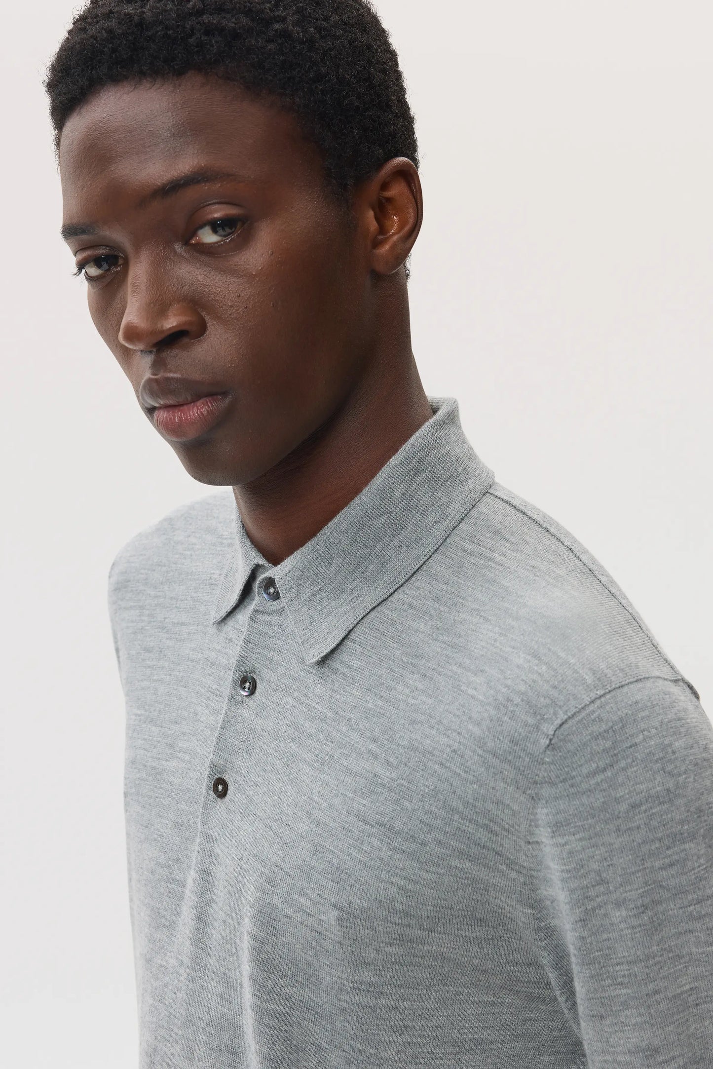Model wears Johnstons of Elgin SS25 Men's Knitwear Light Grey Merino Long Sleeve Polo Shirt on a white backdrop KDI00706HA4183