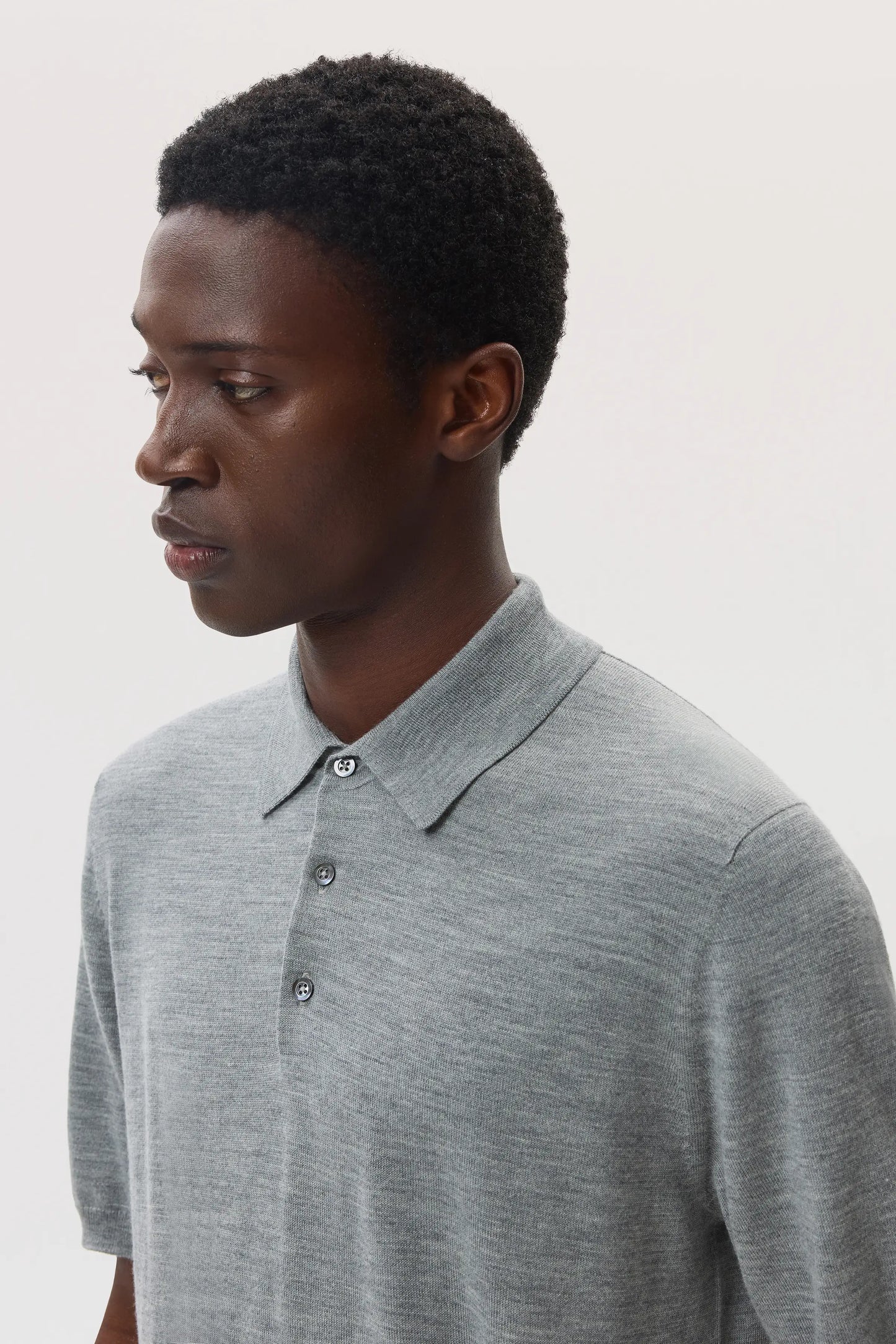 Model wears Johnstons of Elgin SS25 Men's Knitwear Light Grey Superfine Merino Polo Shirt on a white backdrop KDI00715HA4183