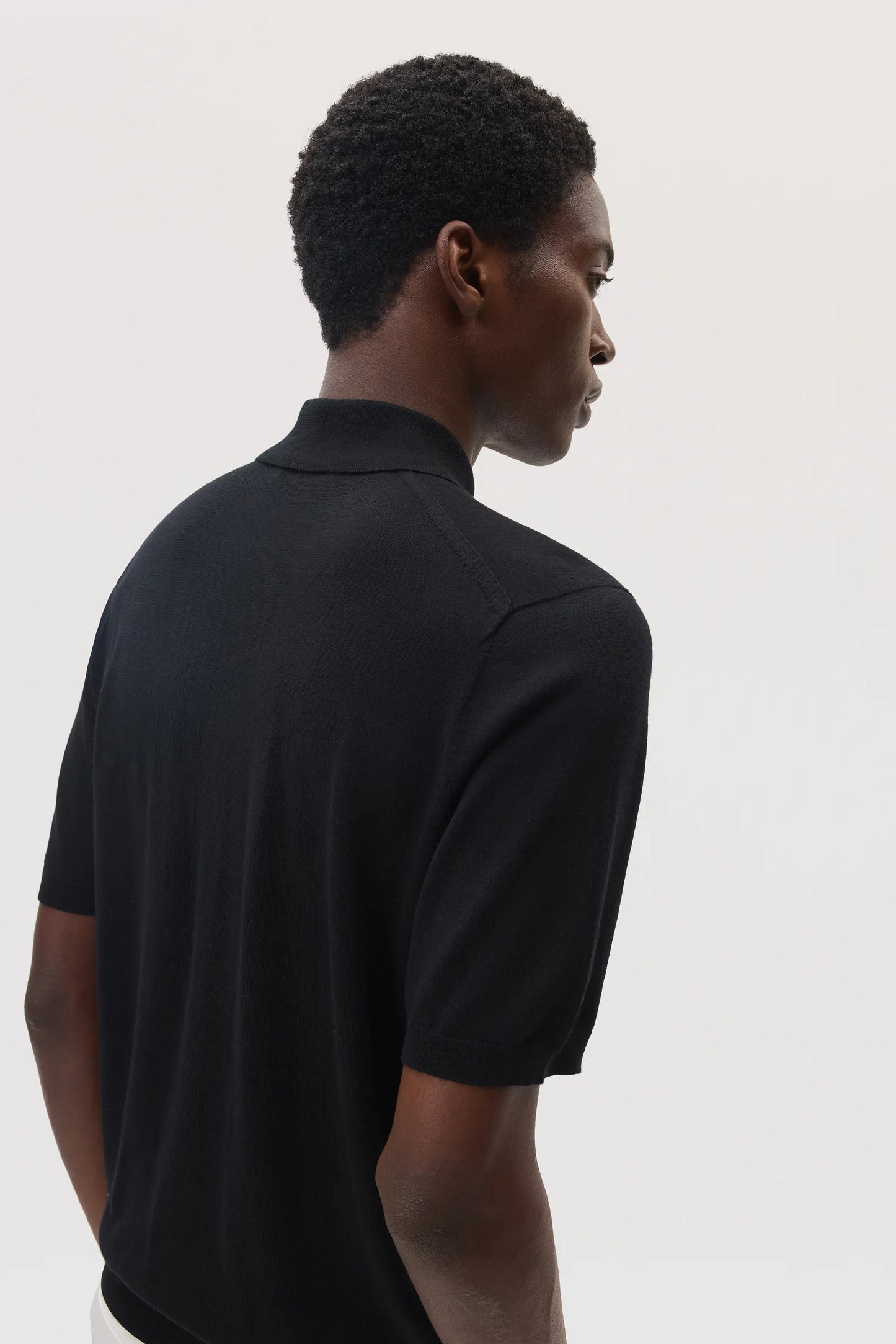 Model wears Johnstons of Elgin SS25 Men's Knitwear Black Superfine Merino Polo Shirt KDI00715SA7131