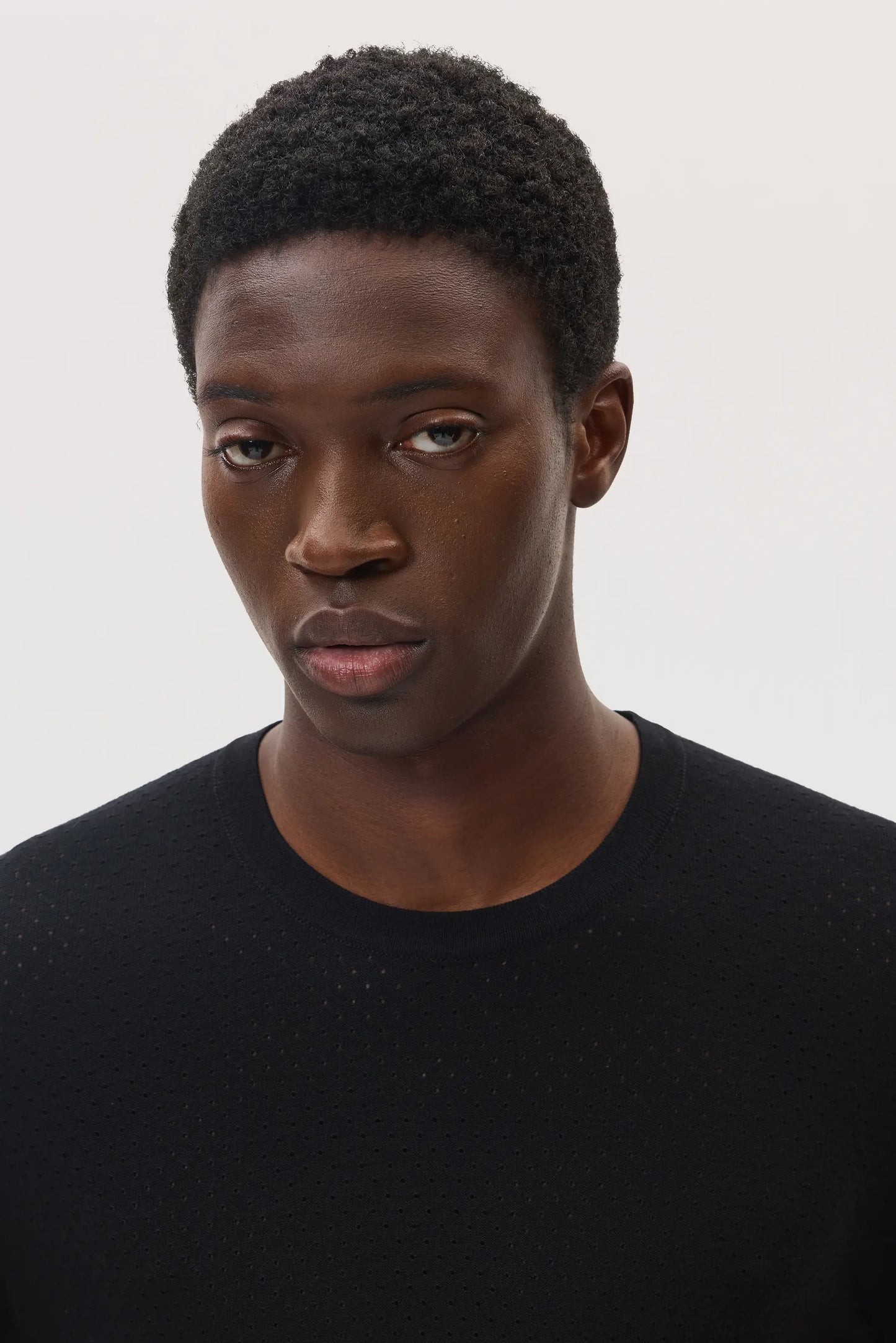 Model wears Johnstons of Elgin SS25 Men's Knitwear Black Superfine Merino Mesh Crew Neck Jumper KDI00729SA7131