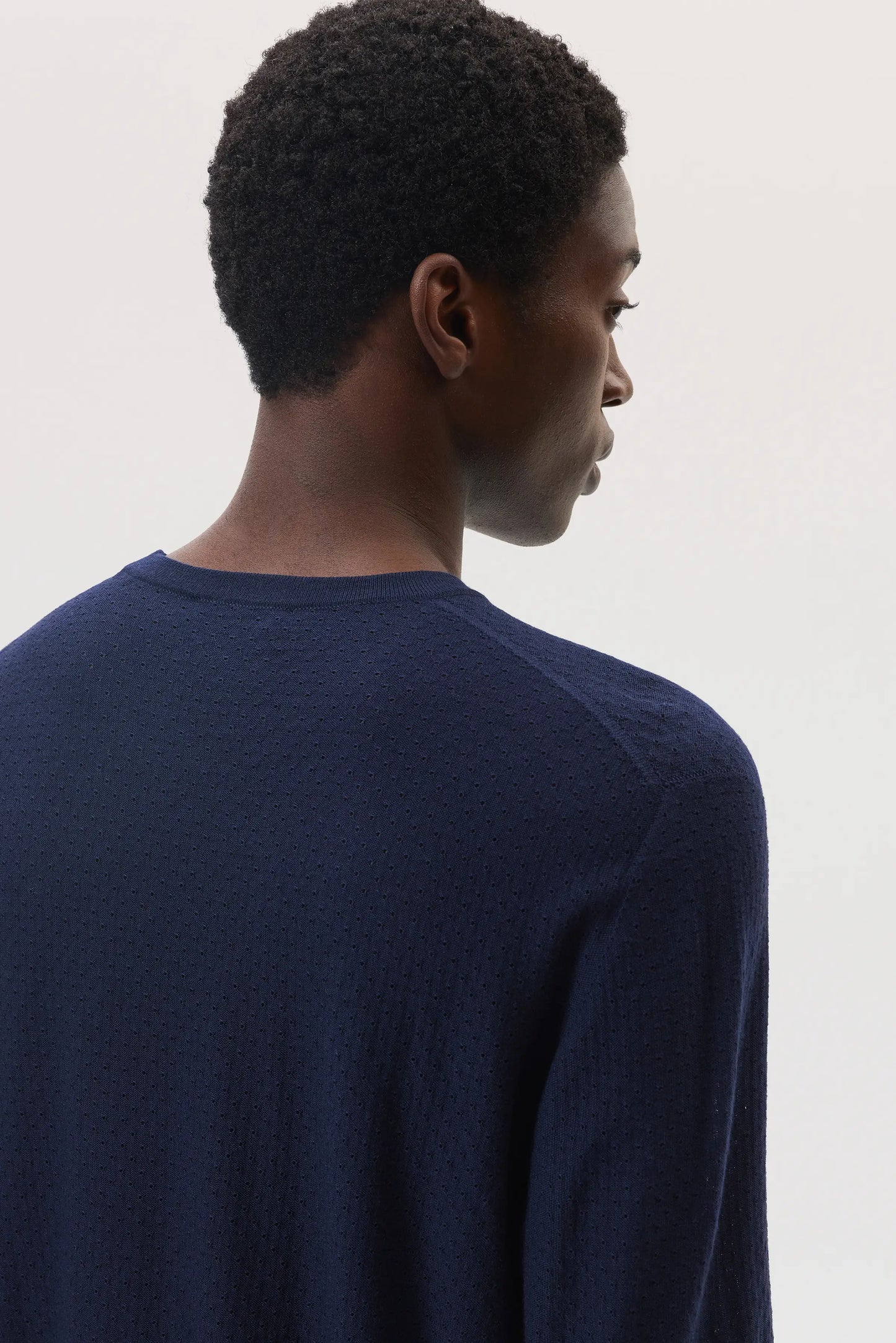 Model wears Johnstons of Elgin SS25 Men's Knitwear Navy Superfine Merino Mesh Crew Neck Jumper against a white background KDI00729SD7563