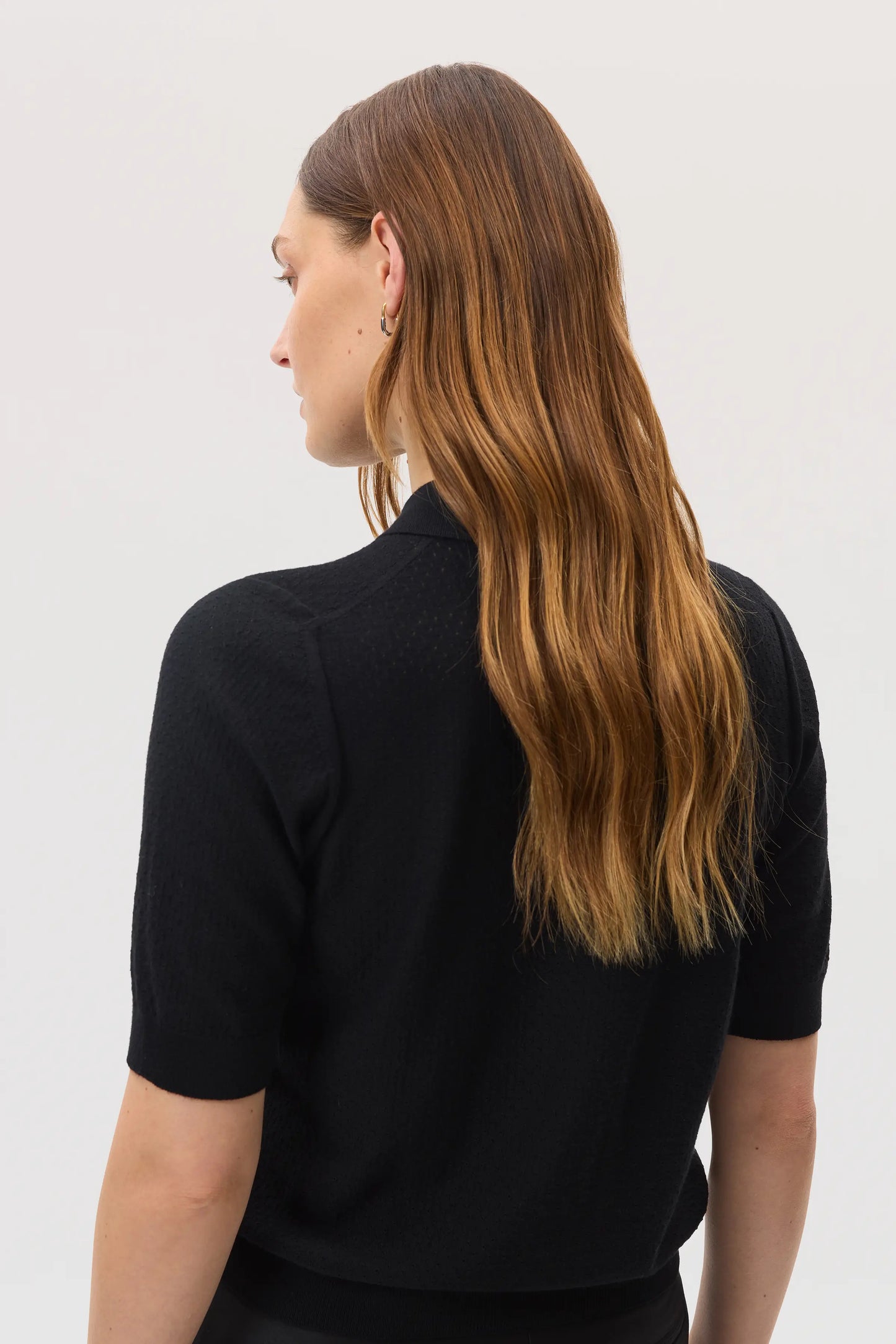 Model wearing Johnstons of Elgin SS25 Women's Knitwear Black Superfine Merino Pointelle Argyle Polo Shirt on a white backdrop KDI00743SA7131