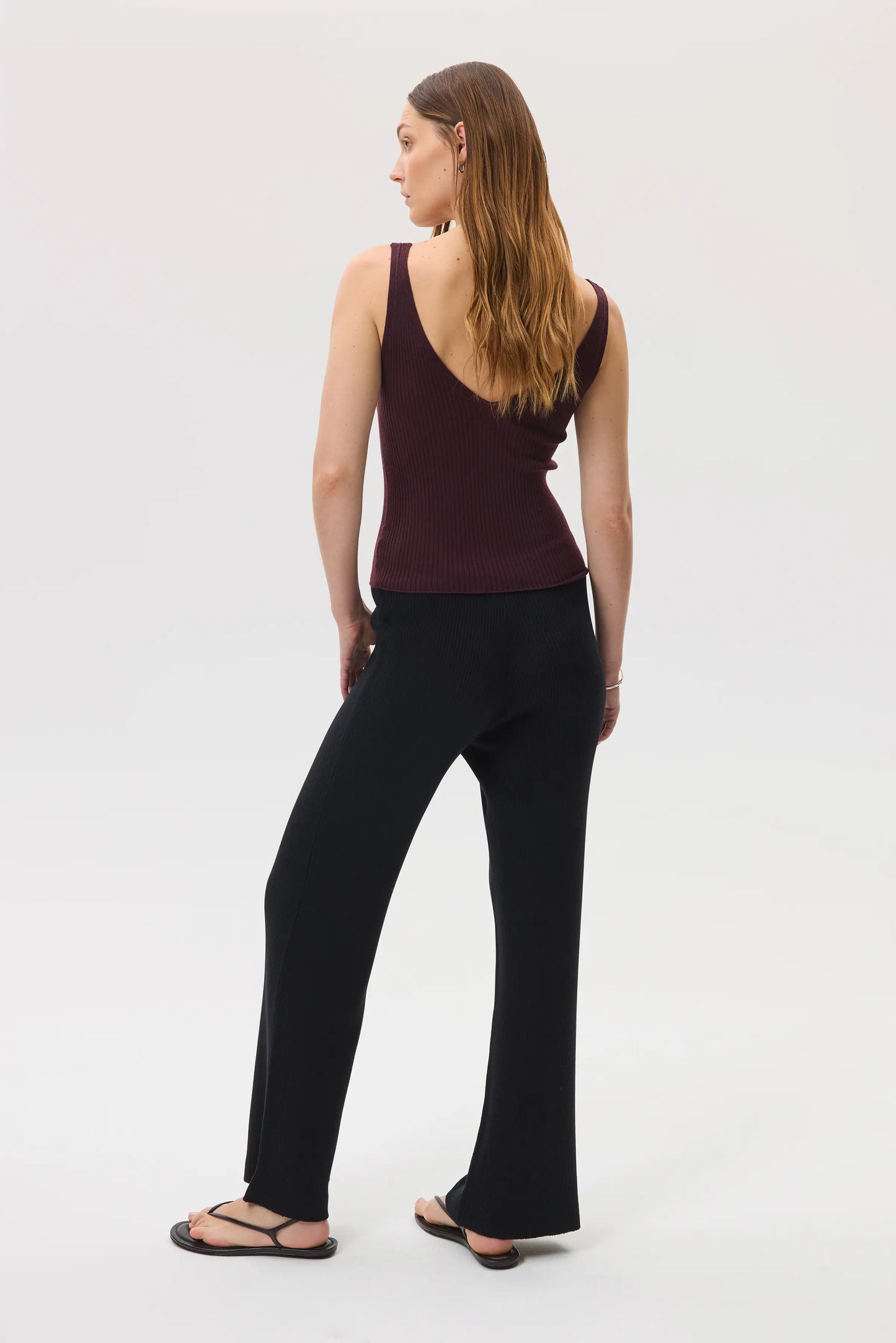 Model wears Johnstons of Elgin SS25 Women's Knitwear Black Ribbed Merino Wide Leg Trousers with our superfine cashmere ribbed vest top in rosewood KDP00746SA7190