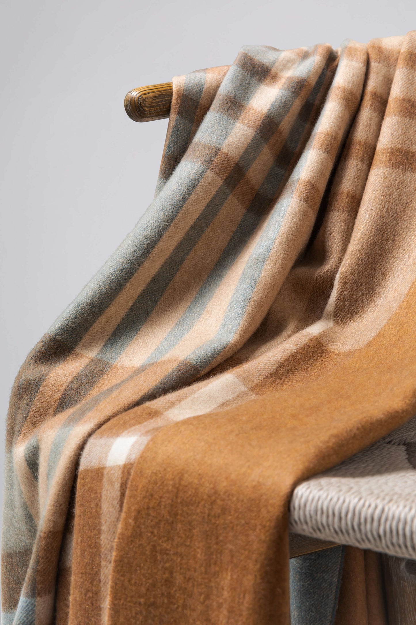 Johnstons of Elgin’s Connon Check Reversible Cashmere Throw on brown chair on a grey background WA000013RU7285