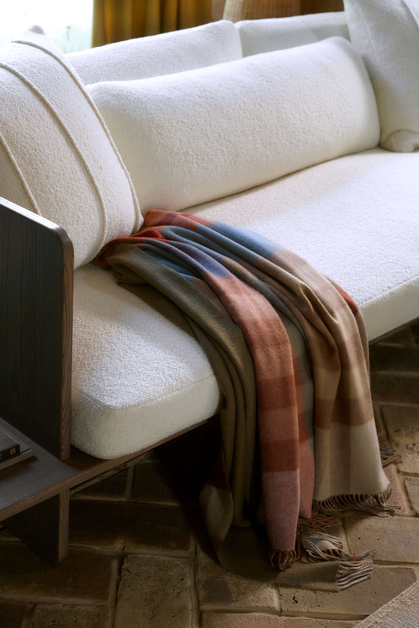 White sofa with a plaid blanket draped over it in a cozy living room setting. WA000013RU7286ONE