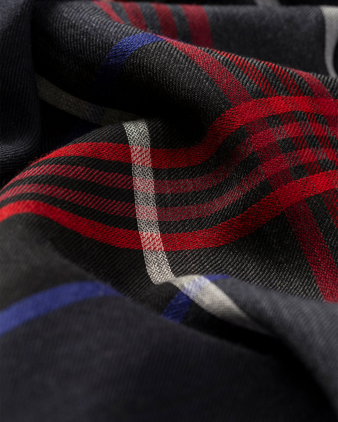 Close-up of a plaid fabric with red, black, and blue stripes. JOHNSTONS OF ELGIN ORTON CRAMMED TARTAN SCARF NAVY 100% CASHMERE WA002447RU7703ONE