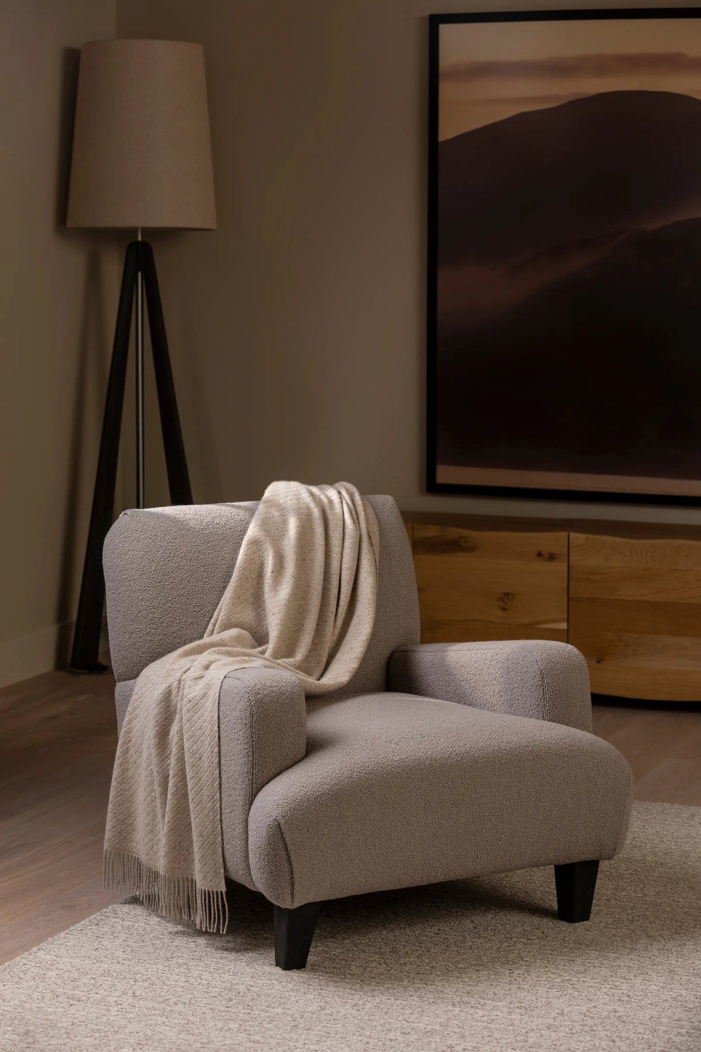 Johnstons of Elgin Interiors Collection Cream Dun Lofty Twill Cashmere Throw draped across a grey upholstered chair in a neutral sitting room setting WAC02308RU7655ONE