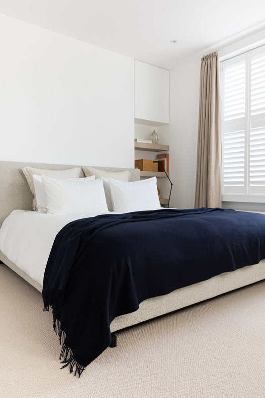 Johnstons of Elgin’s Cashmere Bed Throw in Navy on bed in neutral bedroom WA001159SD7330ONE