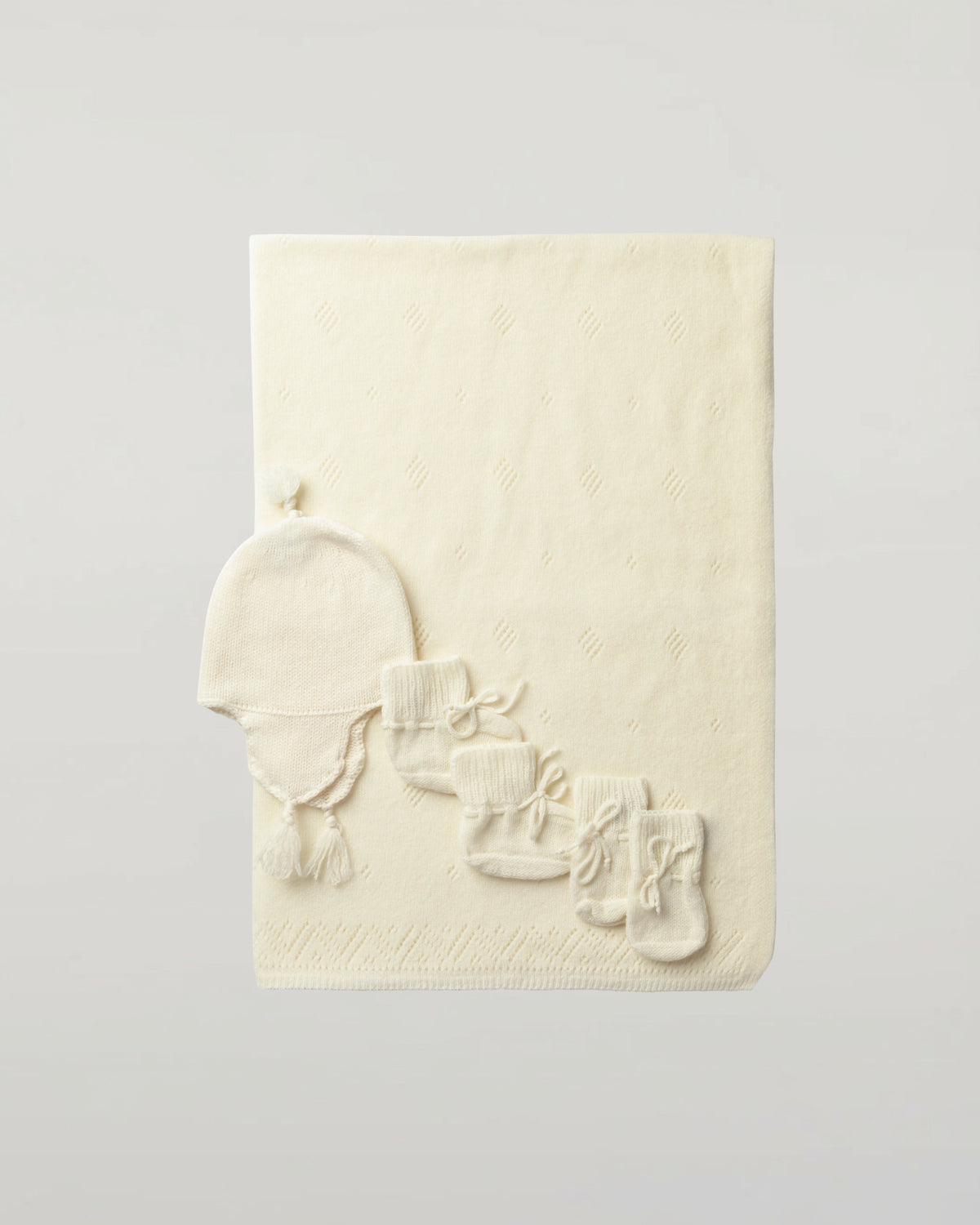 Johnstons of Elgin’s Gift Set includes our Cashmere Pointelle Baby Blanket, Hat, Mittens & Booties in Ecru on a white background AW21GIFTSET18A