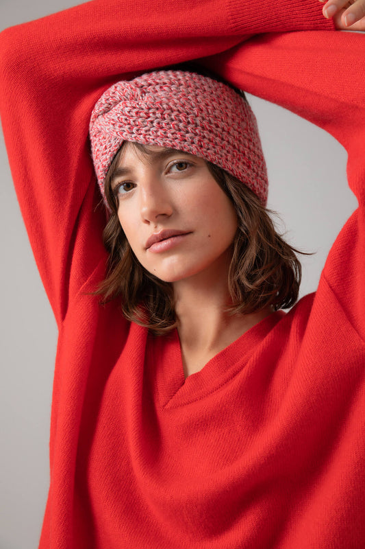 Johnstons of Elgin’s Orkney Red Marl Ribbed Twist Cashmere Headband on model wearing red cashmere jumper on a grey background HAB02942004536ONE