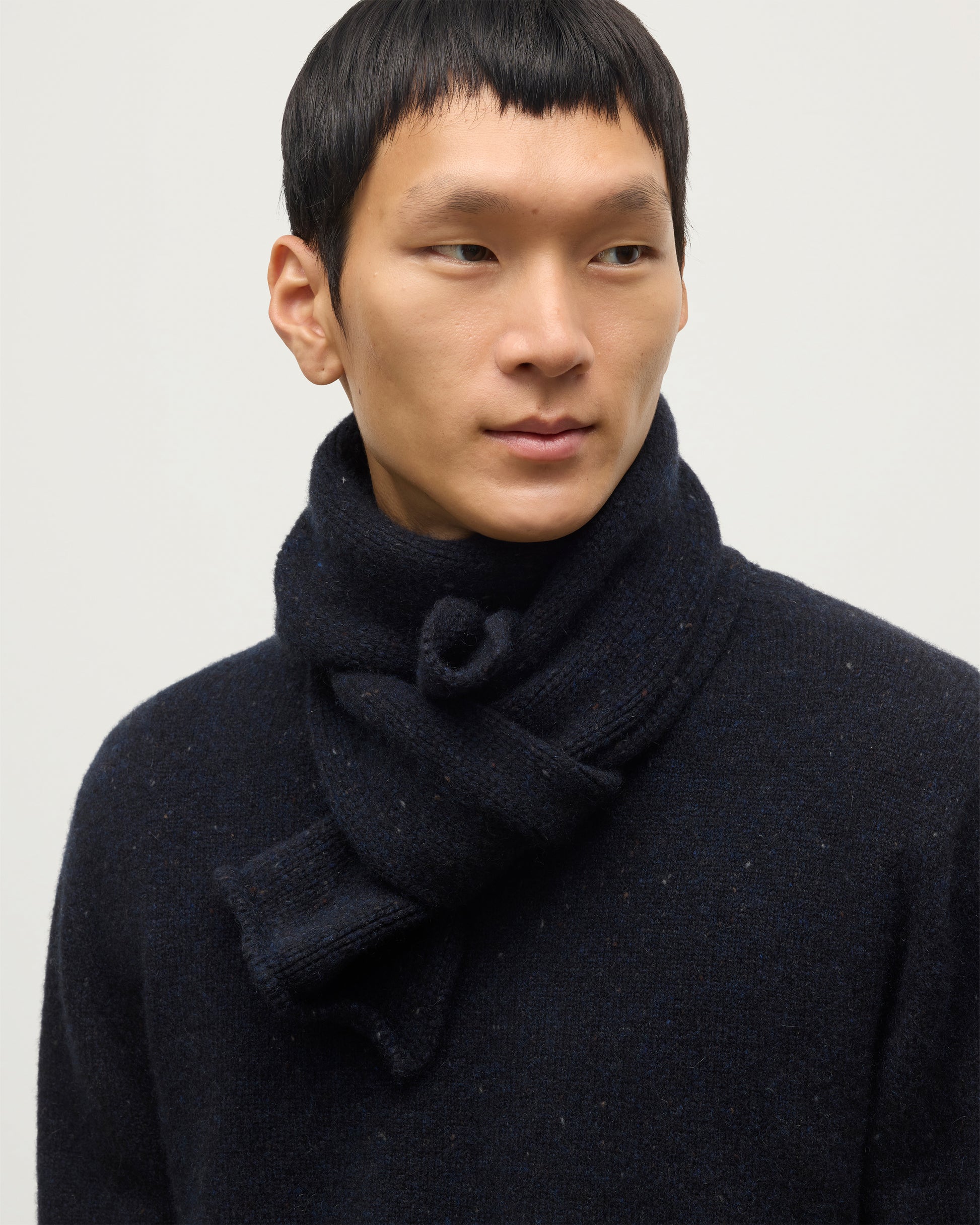 MODEL WEARING JOHNSTONS OF ELGIN TIREE SCARF 100% CASHMERE  WITH MATCHING TIREE CASHMERE SWEATER IN NORTHSCAPE DONEGAL HAC03622HD7348ONE