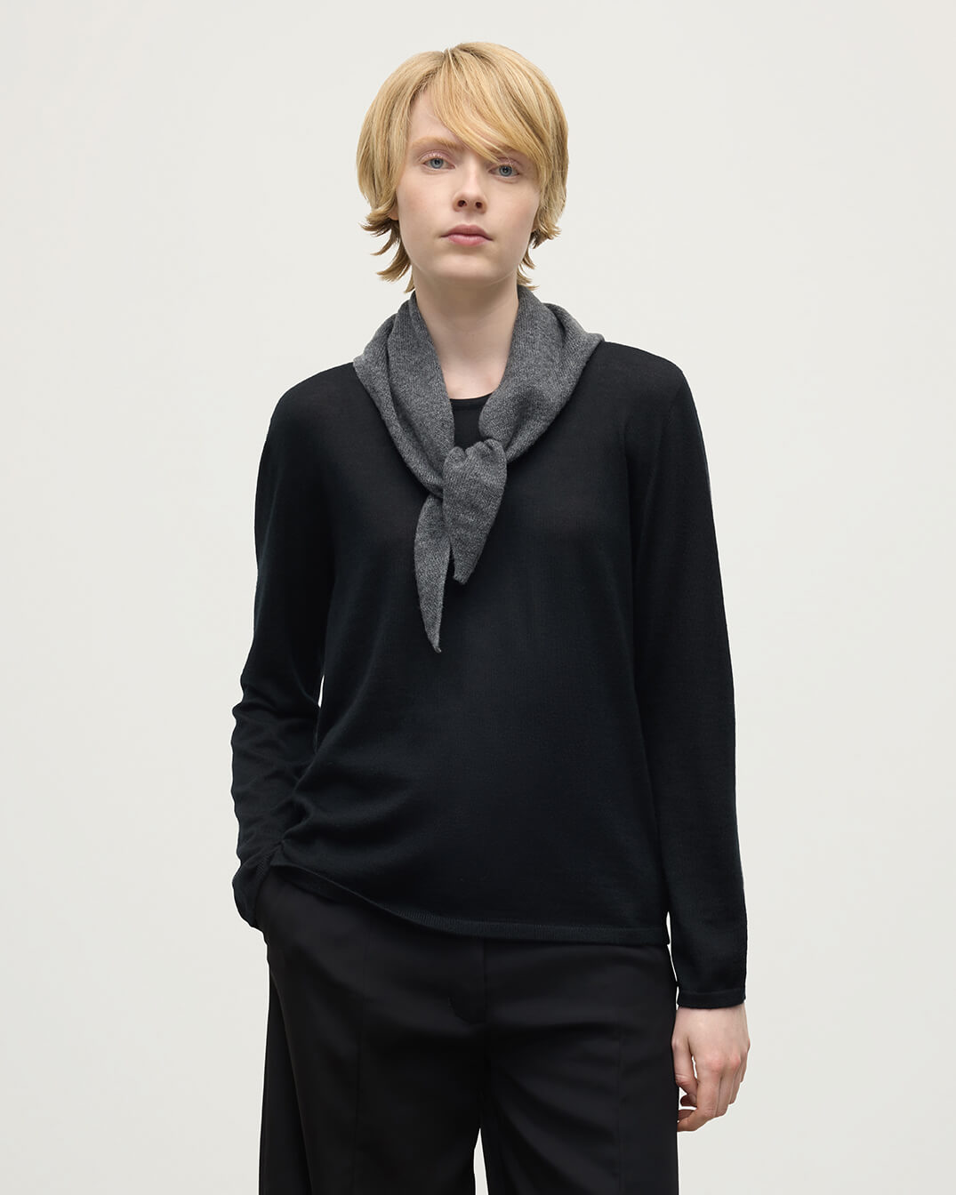 Model wearing Johnstons of Elgin AW25 Knitted Accessories  Gauzy Cashmere Grey Triangle Neck Tie with black cashmere sweater HAE03430HA4181ONE