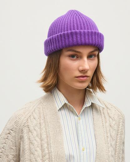 FEMALE MODEL WEARING JOHNSTONS OF ELGIN CASHMERE RIBBED LOVAT BEANIE PURPLE 100% CASHMERE WITH MABEL CABLE CASHMERE CARDIGAN IN WHITE SAND HAY03614SD5371ONE