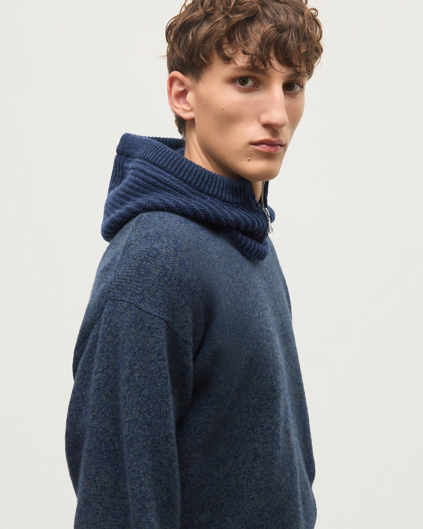 A man wearing a dark navy blue knit sweater with a ribbed high folded collar, shown in a side profile against a plain light gray background. JOHNSTONS OF ELGIN CASHMERE RIBBED NEVIS HOOD WITH ZIP FASTENING NAVY 100% CASHMERE HAY03615Q26296ONE