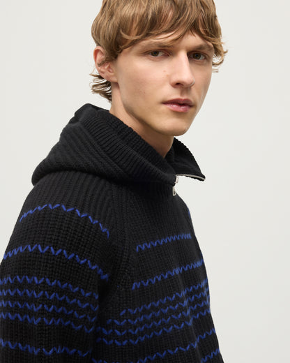 MALE MODEL WEARING JOHNSTONS OF ELGIN NEVIS HOOD BLACK 100% CASHMERE WITH SUMMIT BLACK AND BLUE CASHMERE SWEATER HAY03615Q26168ONE