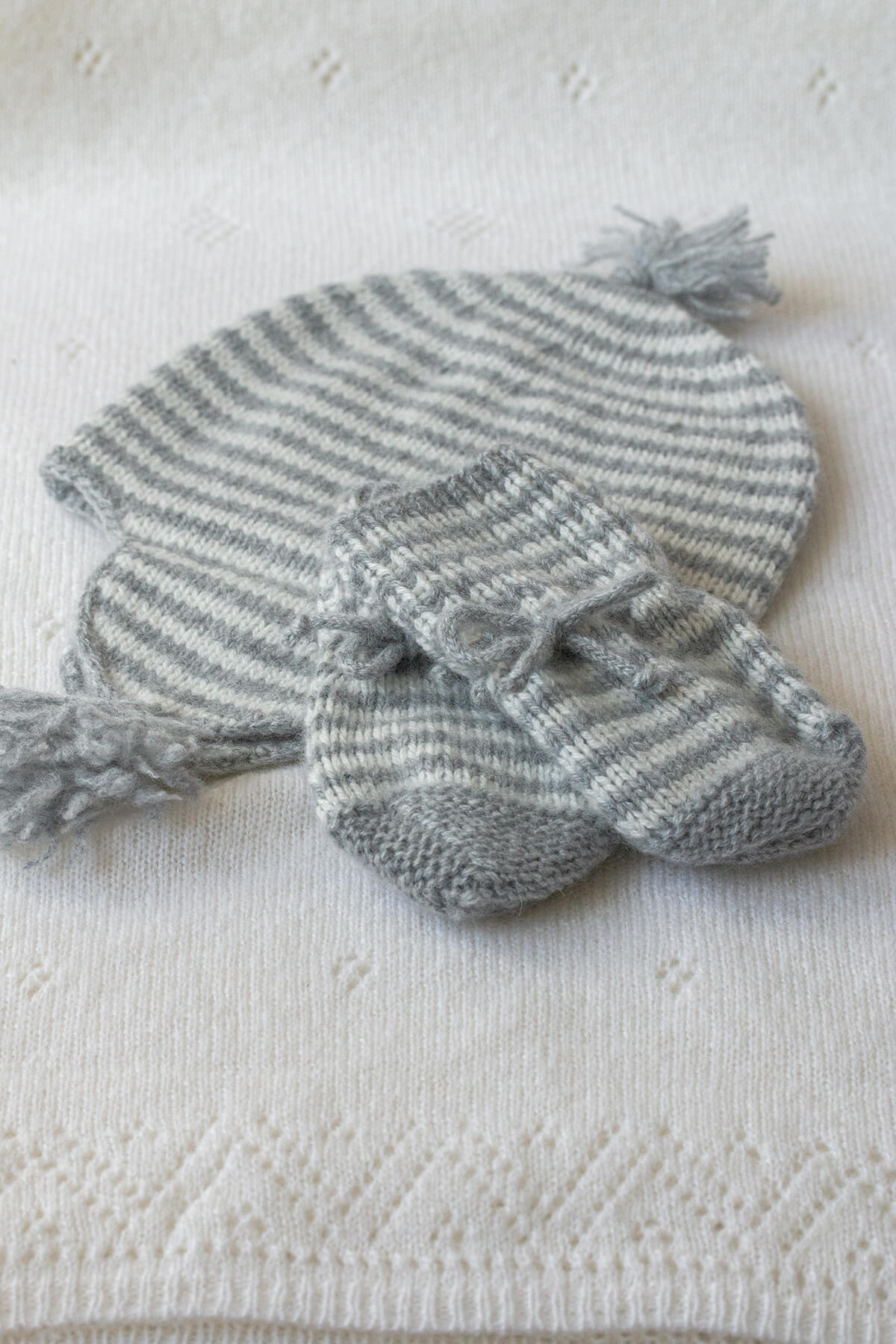 Johnstons of Elgin Hand Knitted Stripe Cashmere Baby Mittens in Silver & White with matching Hat on white background 746344243