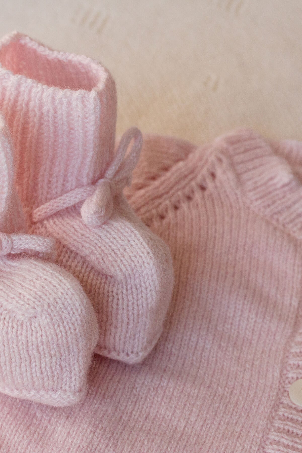 Johnstons of Elgin Hand Knitted Cashmere Baby Cardigan in Blush with matching booties on a white background 30193P191