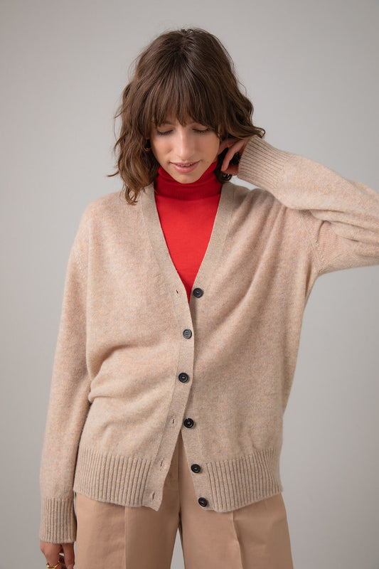 Johnstons of Elgin Gauzy Cashmere Women's V Neck Cardigan in Oatmeal worn over a Red Roll Neck on a grey background KAA04991HB0210