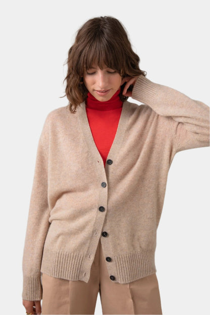 Johnstons of Elgin Gauzy Cashmere Women's V Neck Cardigan in Oatmeal worn over a Red Roll Neck on a grey background KAA04991HB0210