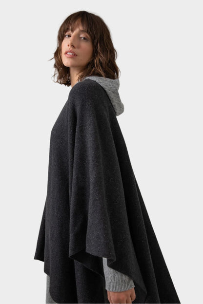 Side of a Johnstons of Elgin Double Face Donegal Cashmere Cape in Charcoal worn with Grey Cable Cashmere Hoodie on a grey background KAA05102Q23681ONE