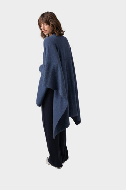 Back of Johnstons of Elgin Double Face Donegal Cashmere Cape in Denim worn with Navy Cashmere Sweater and Wide Leg Joggers on a grey background KAA05102Q23736ONE