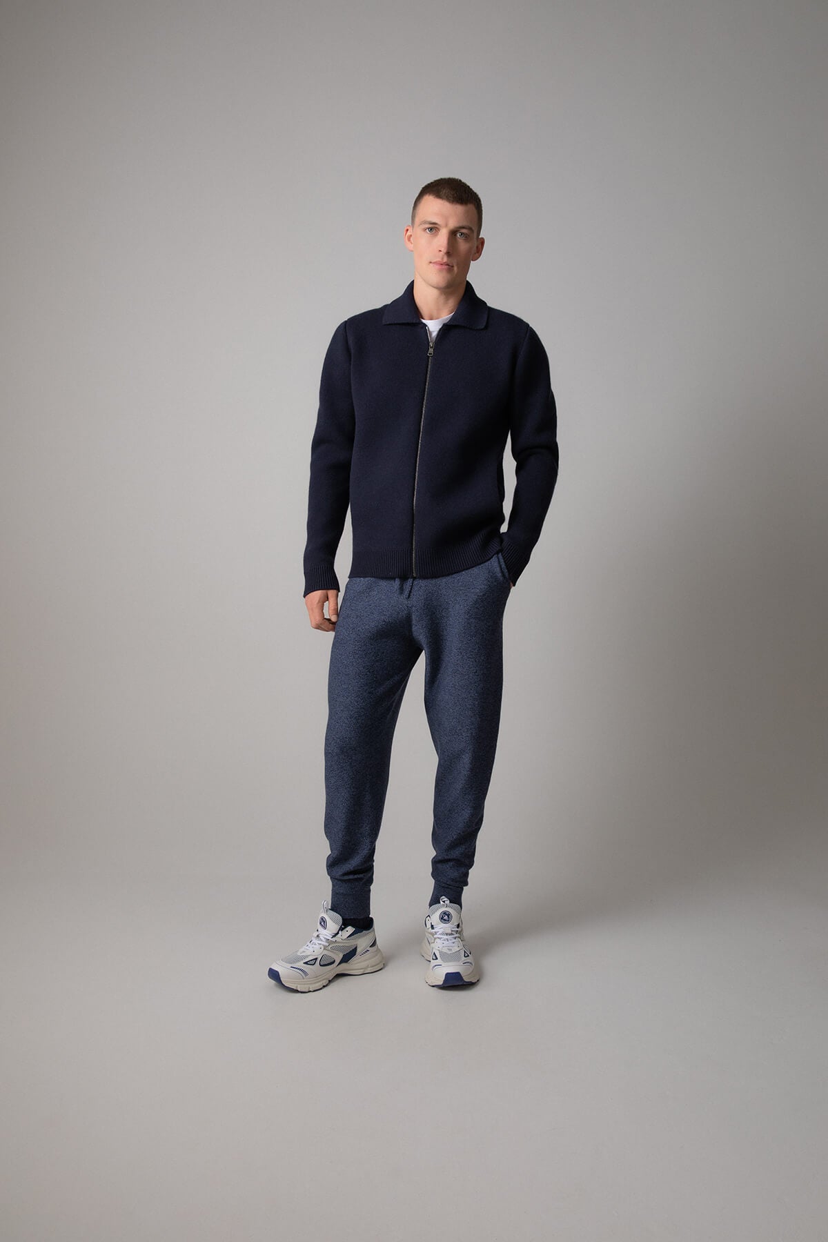Johnstons of Elgin’s Men's Milano Stitch Cashmere Zip Jacket in Dark Navy on model wearing blue joggers on a grey background KAA05113SD7286