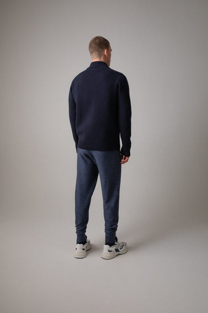 Johnstons of Elgin’s Men's Milano Stitch Cashmere Zip Jacket in Dark Navy on model wearing blue joggers on a grey background KAA05113SD7286